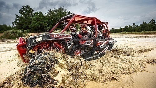 Red and Black Polaris UTV riding through mud puddle